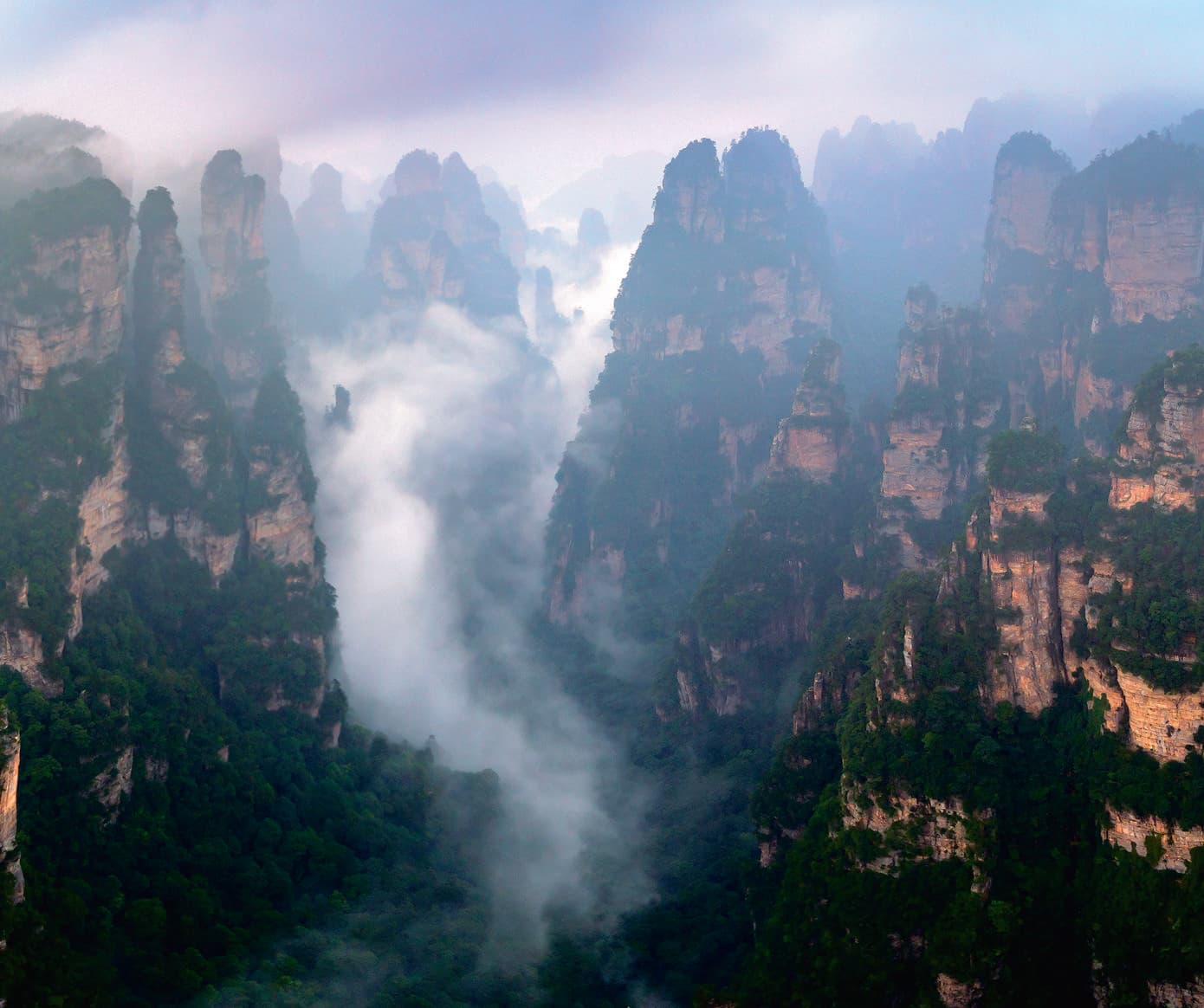 Official Tour Guide Manual photograph of mist moving through Yuanjiajie peak forest