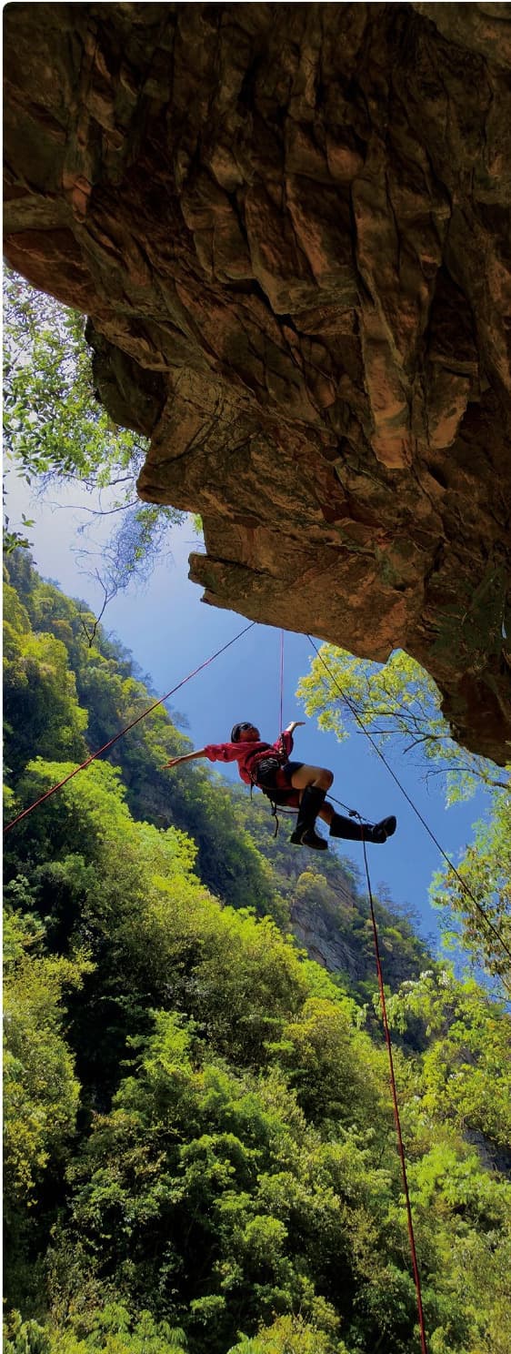 Roped climber beneath a sandstone overhang in Baihutang Wild Fun Valley