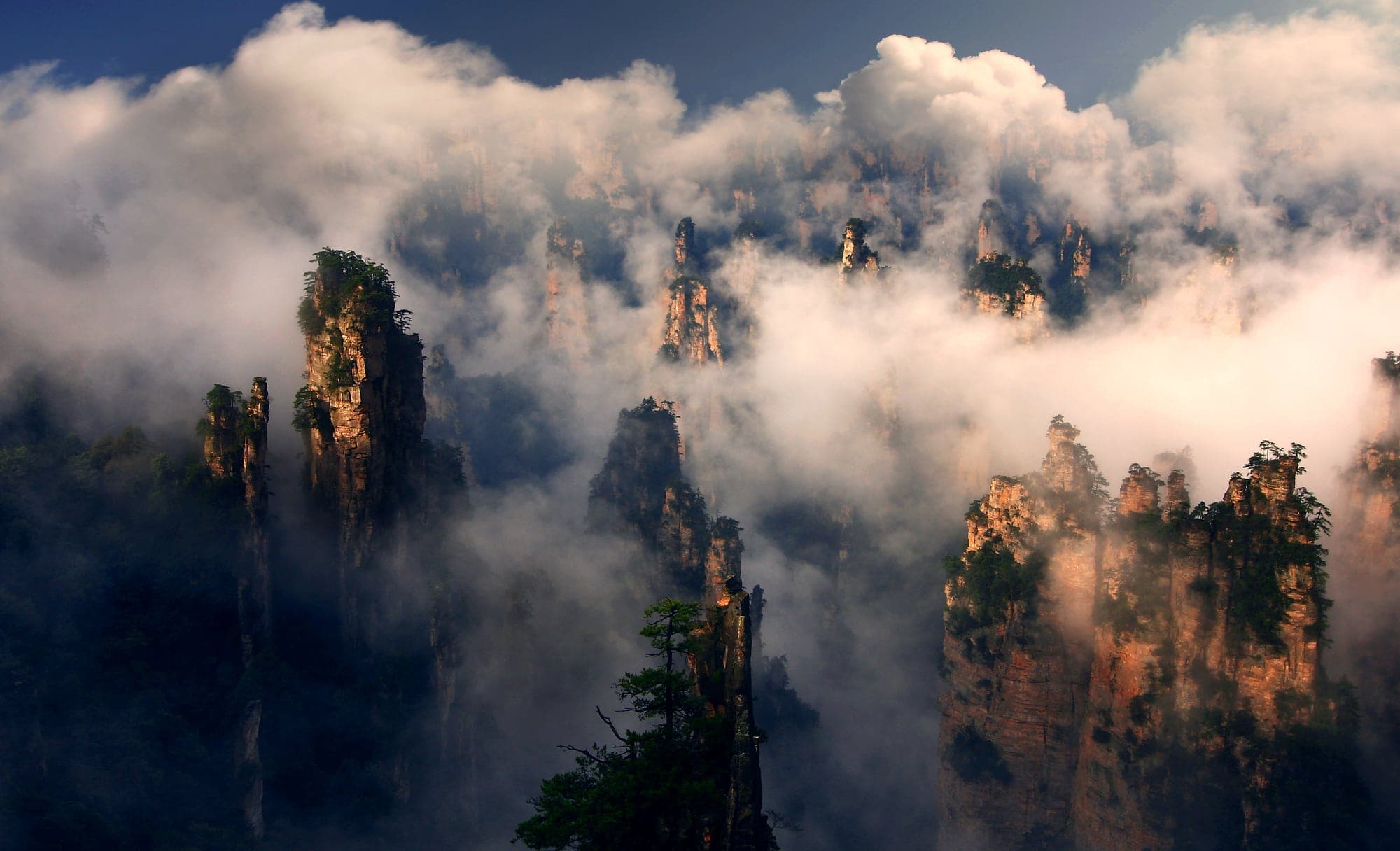 Sandstone pillars catching warm light through moving clouds.