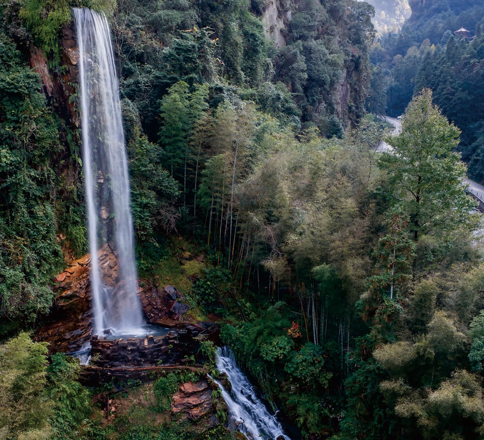 A waterfall and forest route in the wider Zhangjiajie landscape documented in the official Tour Guide Manual.